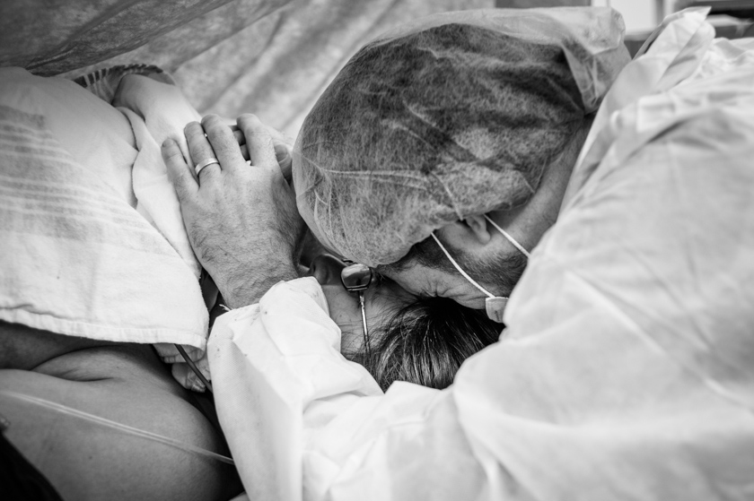 father hugging mother and child right after delivery