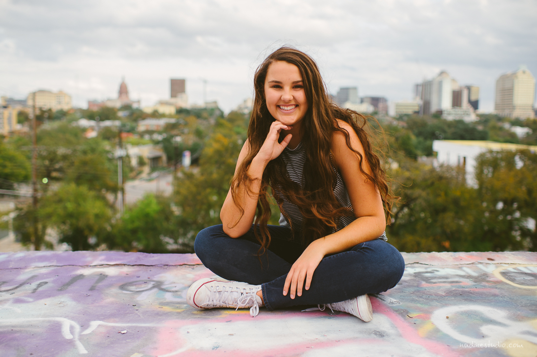 senior pics graffiti wall austin with the sky line in the background